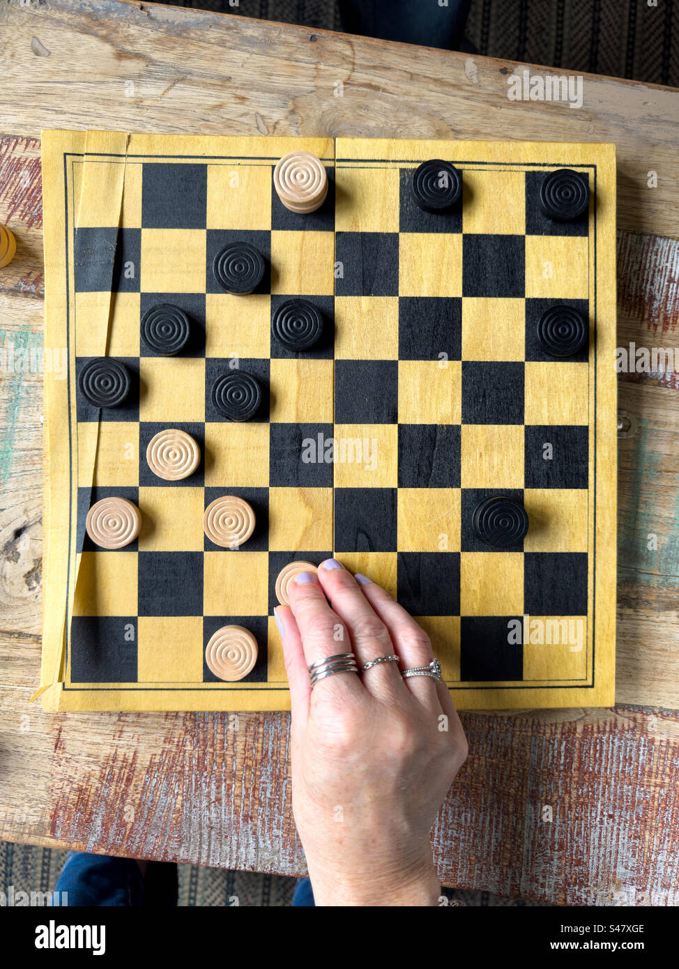 Female hand moving a checker piece. Top view - Smartphone Captured Stock Image