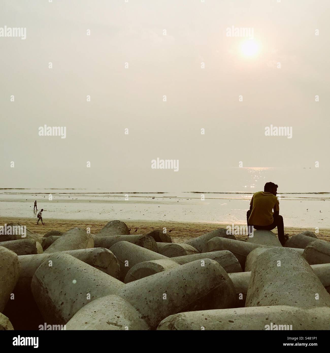 Man sitting on a pod on Versova beach in Mumbai - Smartphone Captured Stock Image