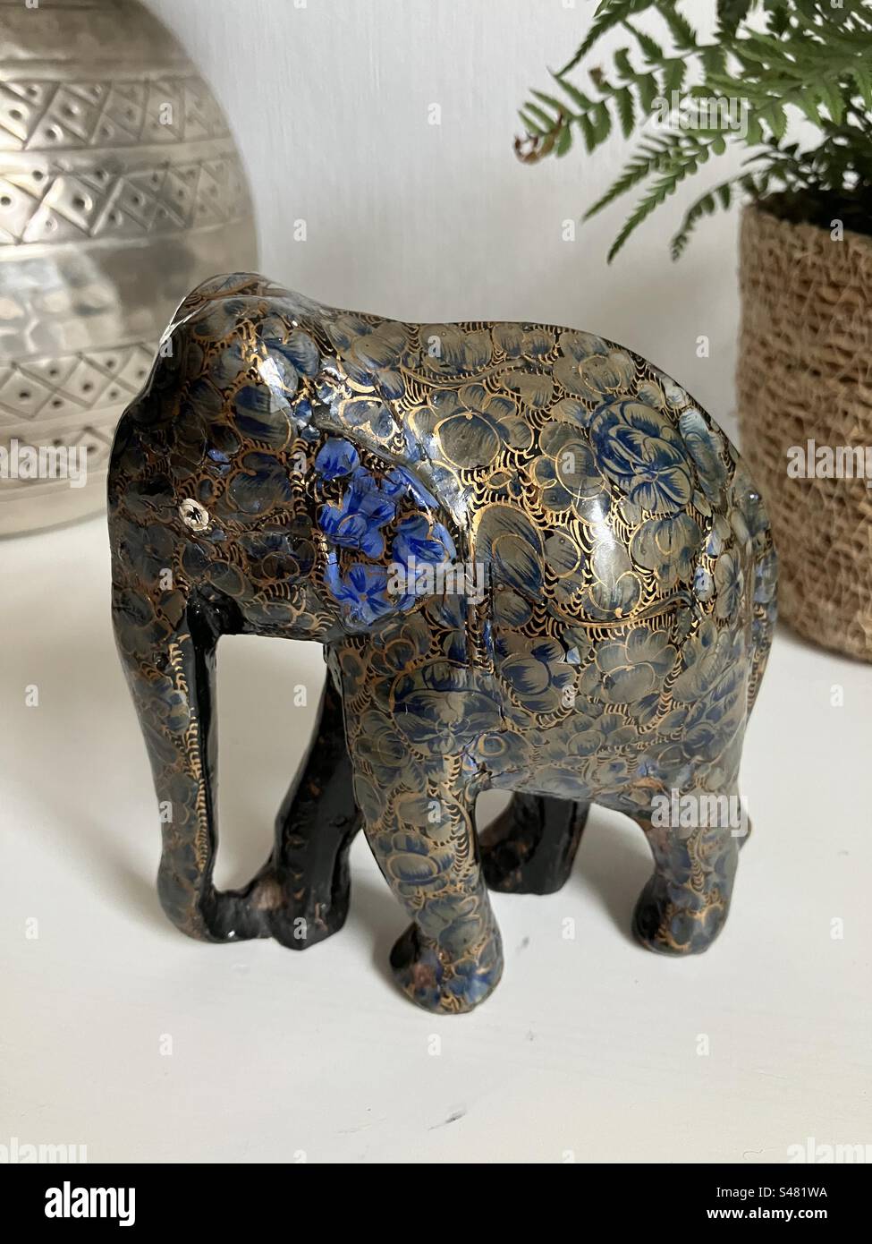 Paper mache ornament elephant in blue and gold stood on a white wooden