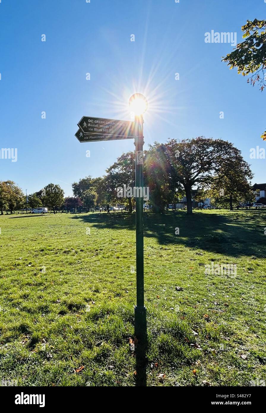 Sun shining through the top of a sign post in suburban london part of the green chain walk Stock Photo