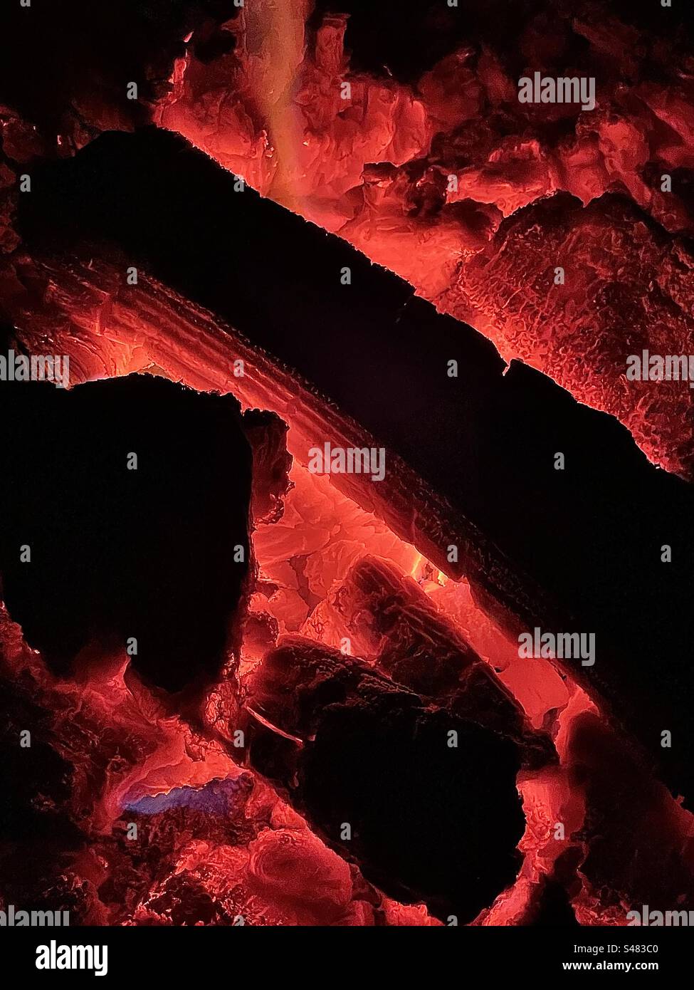 A closeup view of the inside of an outdoor fire pit. The wood has burned down to be pretty much just red hot coals. A fine fiery abstract. - Smartphone Captured Stock Image