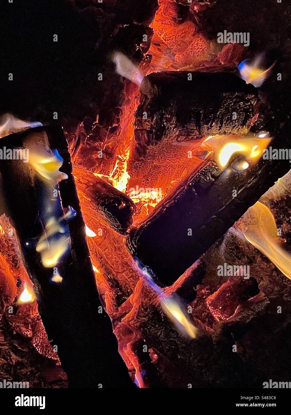 A closeup view of the inside of an outdoor fire pit. The wood has burned down to be pretty much just red hot coals. A fine fiery abstract. - Smartphone Captured Stock Image