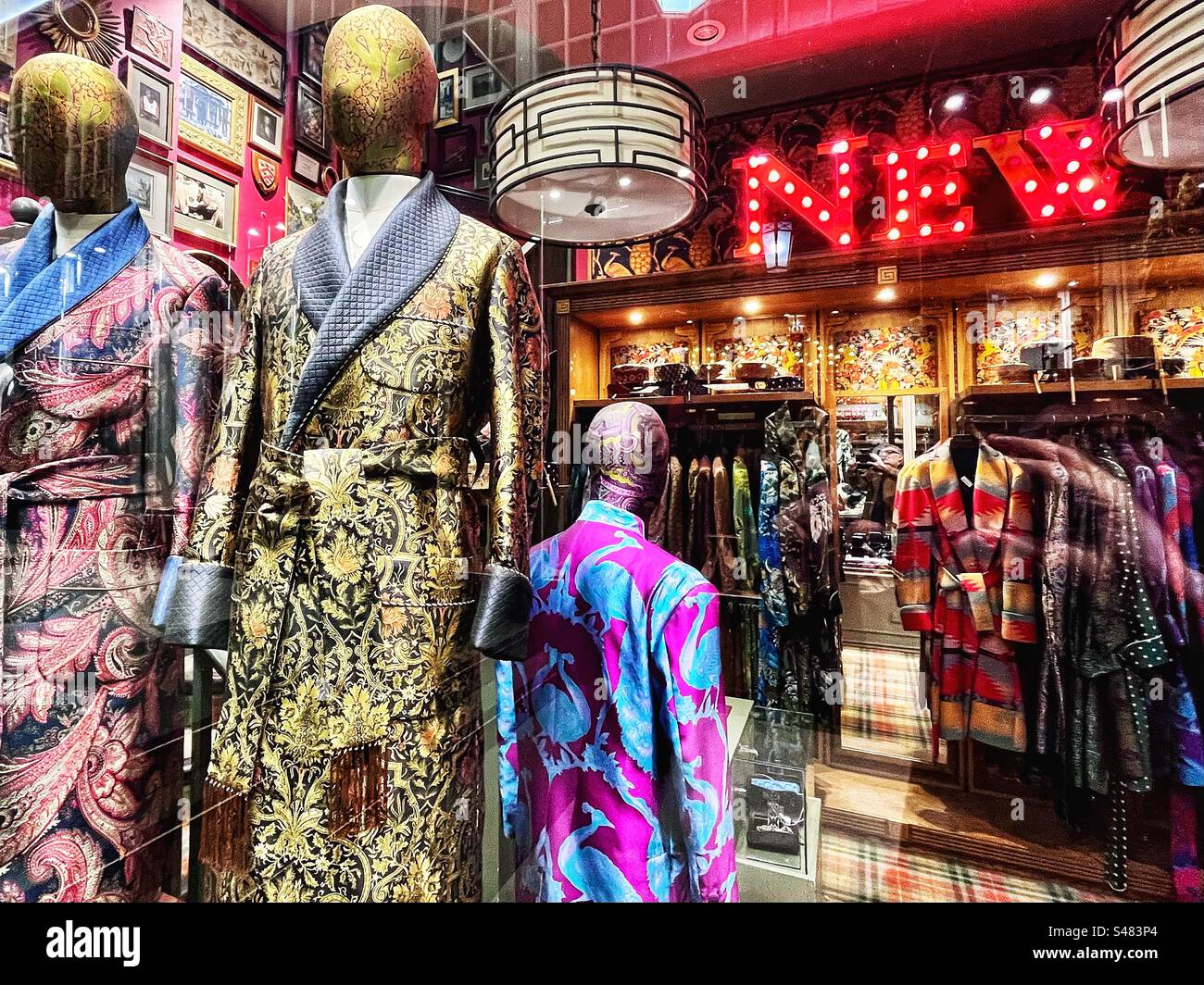 Design clothes in Grade II Listed Piccadilly Arcade shop that runs between Piccadilly and Jermyn Street in London. Seen lit at night. - Smartphone Captured Stock Image