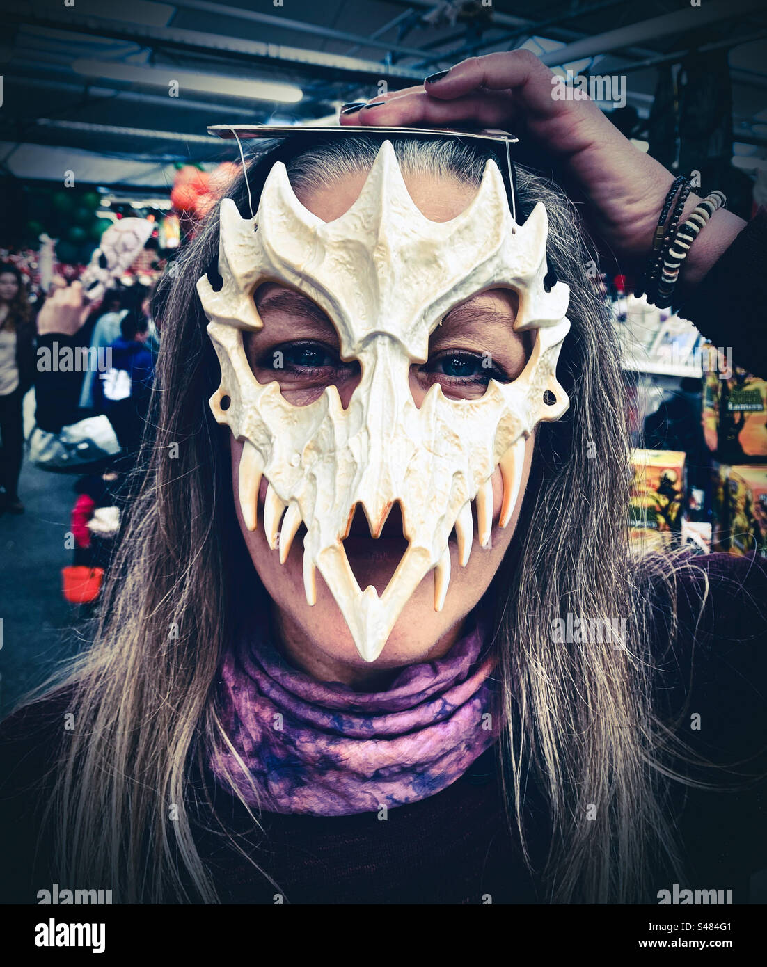 A woman tries an a halloween mask at a party shop Stock Photo