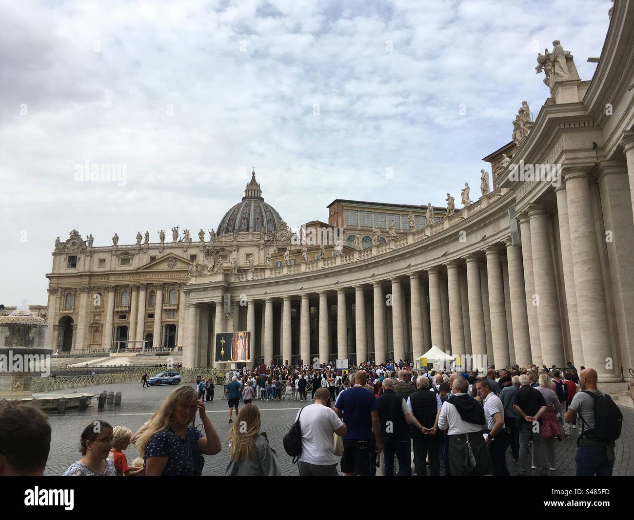 Fila di turisti e pellegrini per visitare la Basilica di san Pietro. Vaticano, Roma. Colonnato di destra. Veduta parziale della Basilica, Cupola. Stock Photo