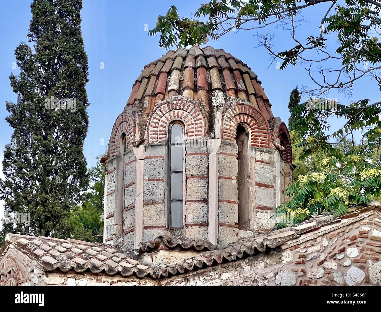 Blue early evening sky and trees back the dome and roof of the quaint Holy Church of the Transfiguration of the Savior in Plaka neighborhood of Athens - Smartphone Captured Stock Image
