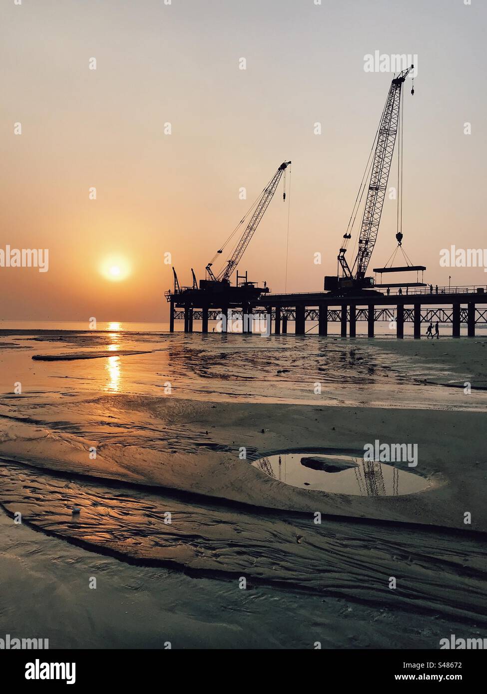 Heavy machinery used for road construction on a beach during sunset - Smartphone Captured Stock Image