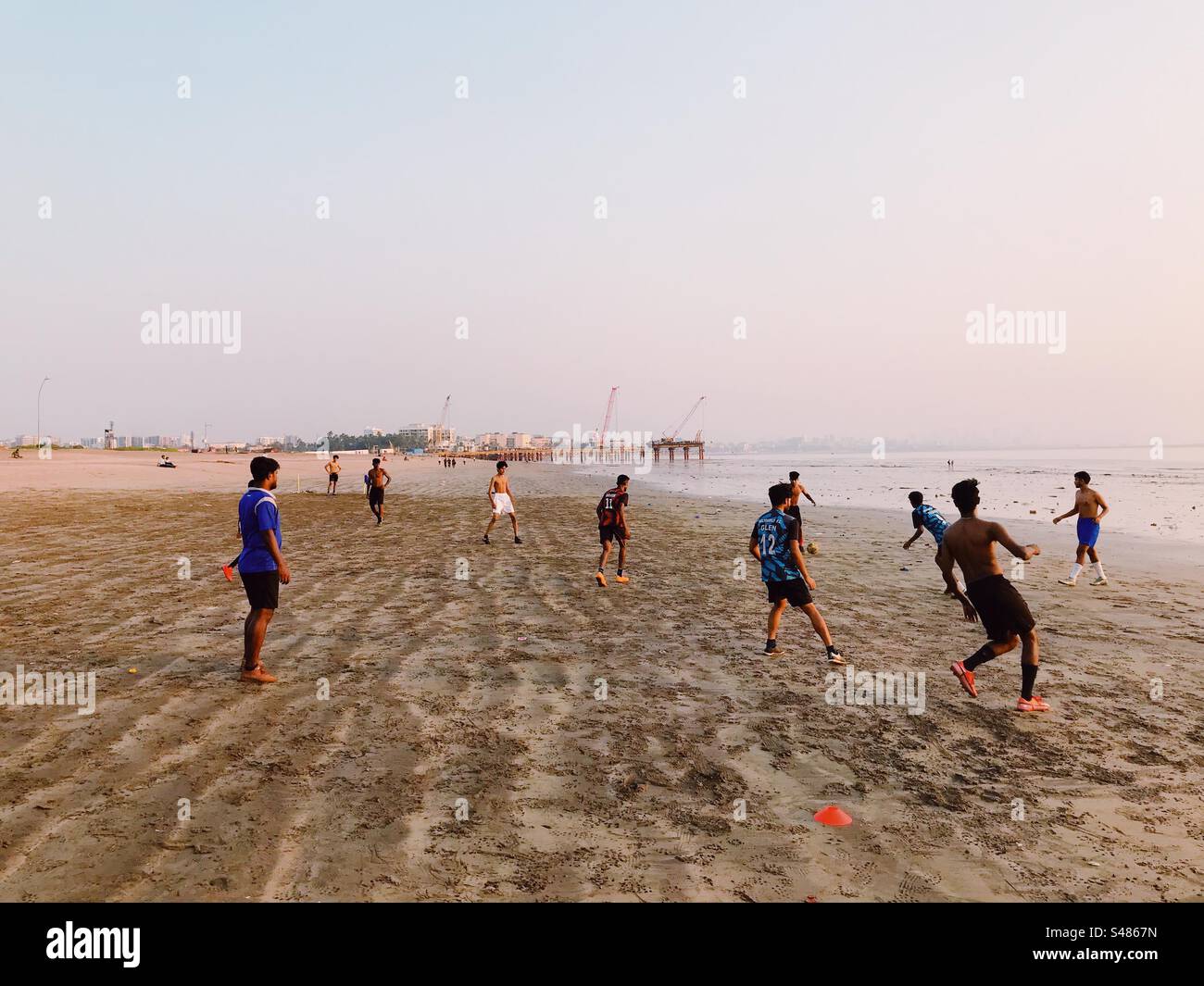 Young adults playing football or soccer on a beach - Smartphone Captured Stock Image