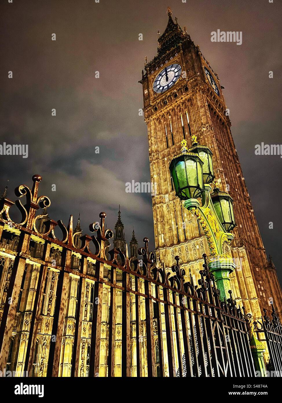 Big Ben at midnight - the clock tower of the Houses of Parliament in London seen at night with heritage lamps shining - Smartphone Captured Stock Image