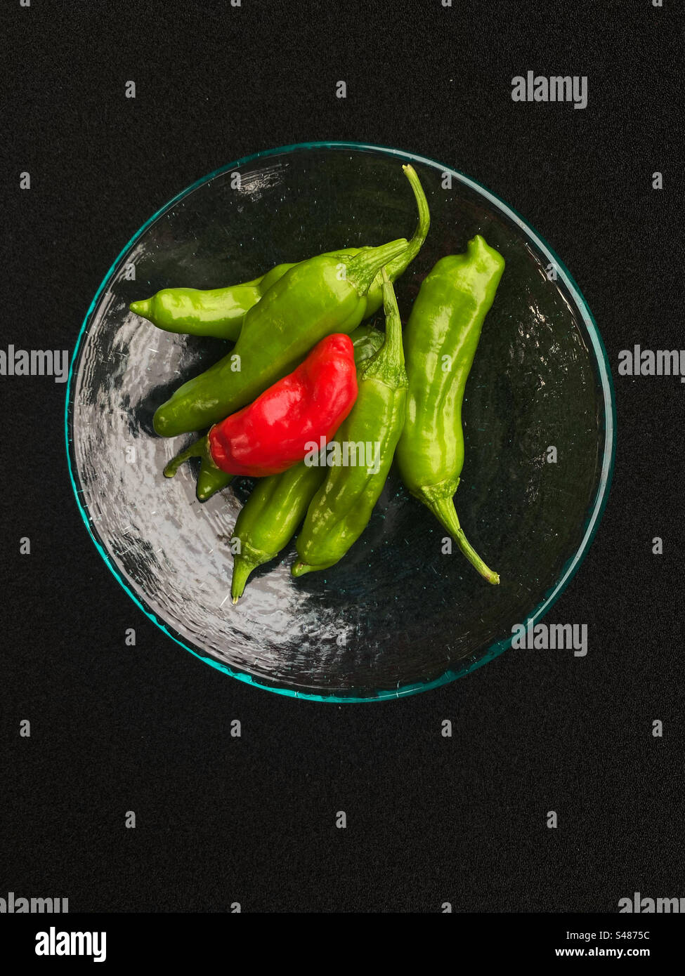 Shishito peppers on a glass dish with a black background - Smartphone Captured Stock Image