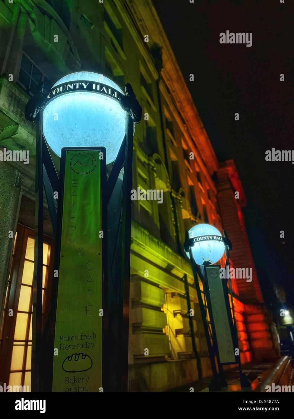 Lamps say County Hall once the home of the GLC and LCC - local government in London. Seen at night illuminated - Smartphone Captured Stock Image