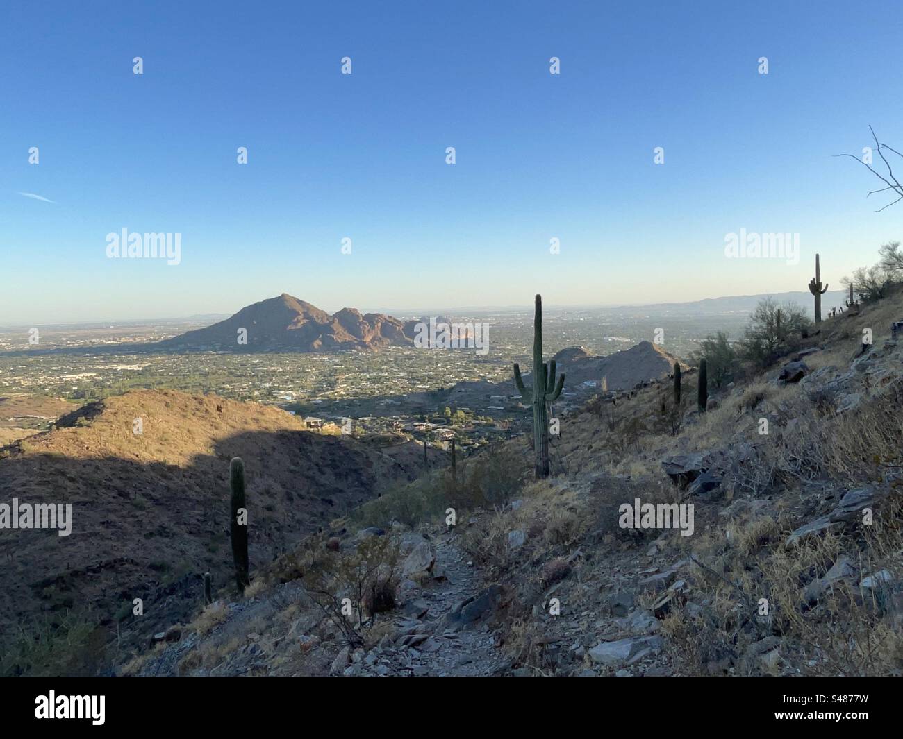 Camelback mountain with setting sun glow, view from hiking trail, banded blue and orange sunset, saguaros, Phoenix Mountains Preserve, Arizona Stock Photo