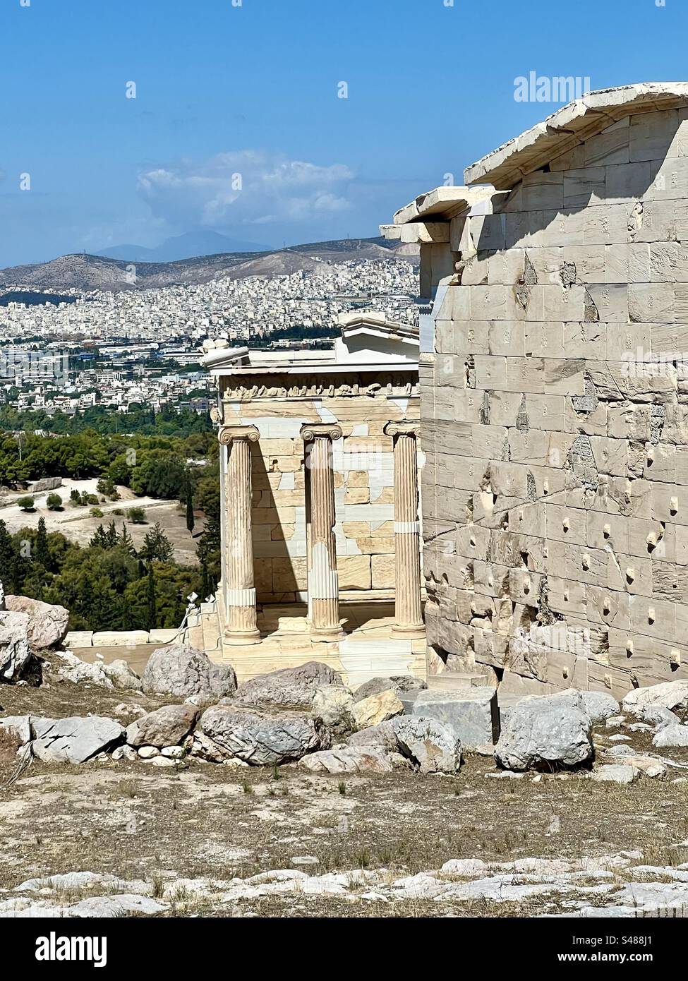 Temple  of Athena Nike, goddess of victory, amongst the amazing ruins on Acropolis Hill with the city of Athens and mountains in the background. - Smartphone Captured Stock Image