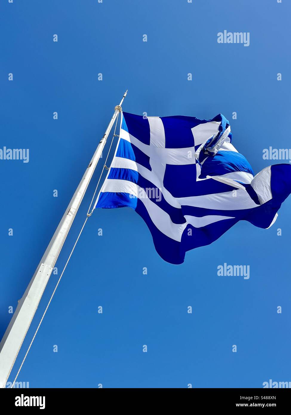 Blue and white flag of Greece atop the ancient archaeological site of Acropolis in Athens - Smartphone Captured Stock Image