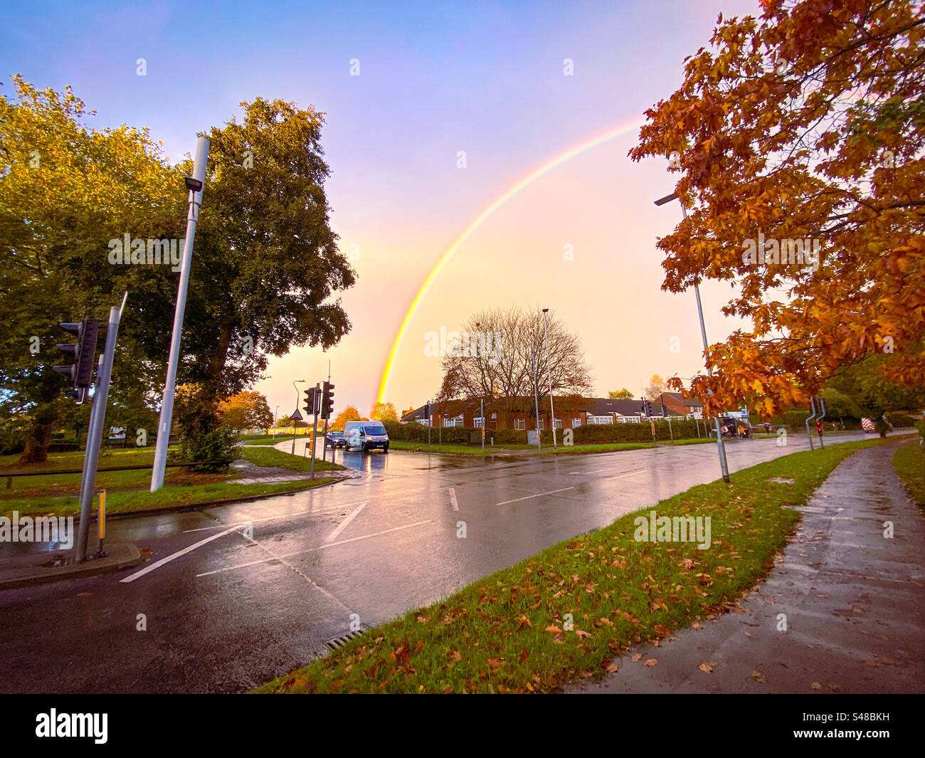 A colourful rainbow arches over a road junction in Reading, UK - Smartphone Captured Stock Image