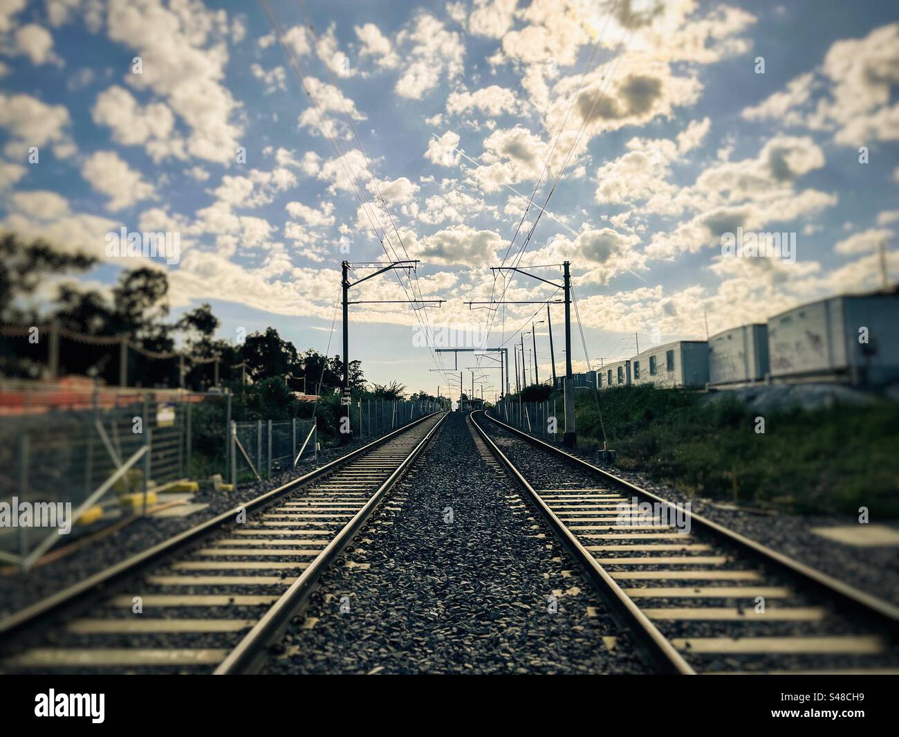 Railroad tracks under a moody cloudy sky. Travel. Diminishing perspective. Vanishing point. The way forward. - Smartphone Captured Stock Image