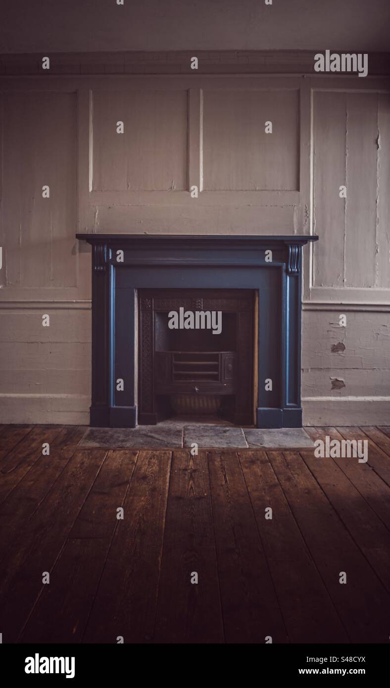 Abandoned home interior of a coal fireplace in a cold house with wooden floor during the energy crisis in Winter with copy space - Smartphone Captured Stock Image
