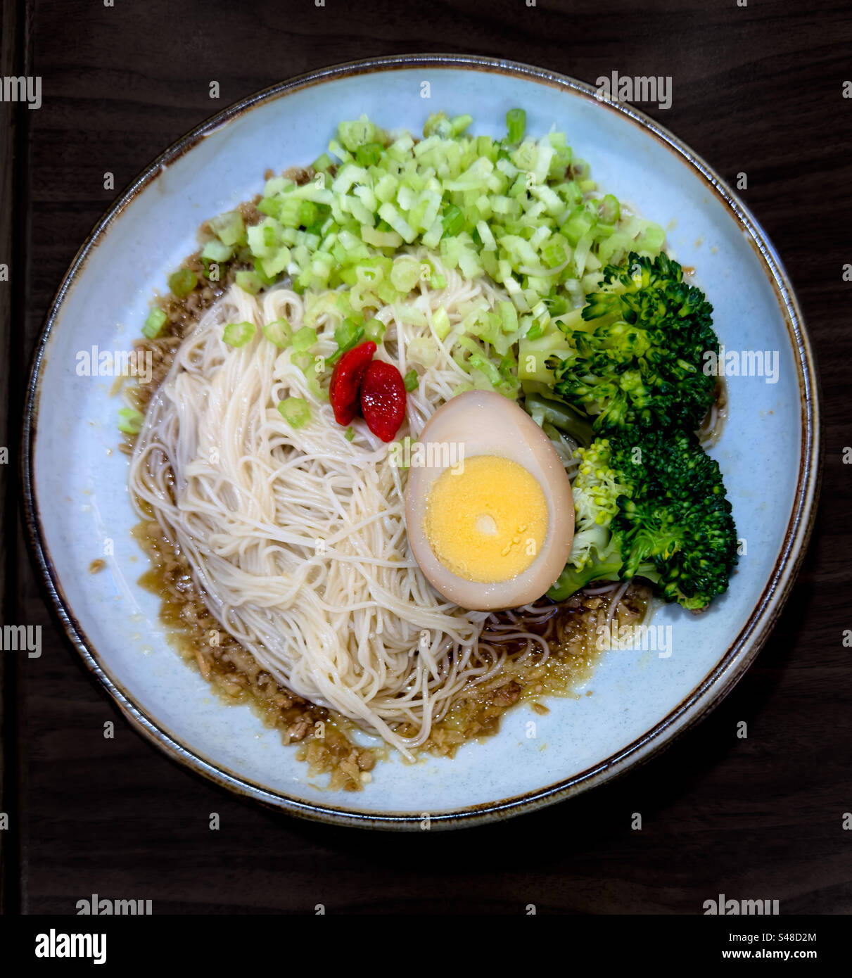 Plate of cold Chinese noodles served on top of minced meat sauce, garnished with soy egg and vegetables - Smartphone Captured Stock Image