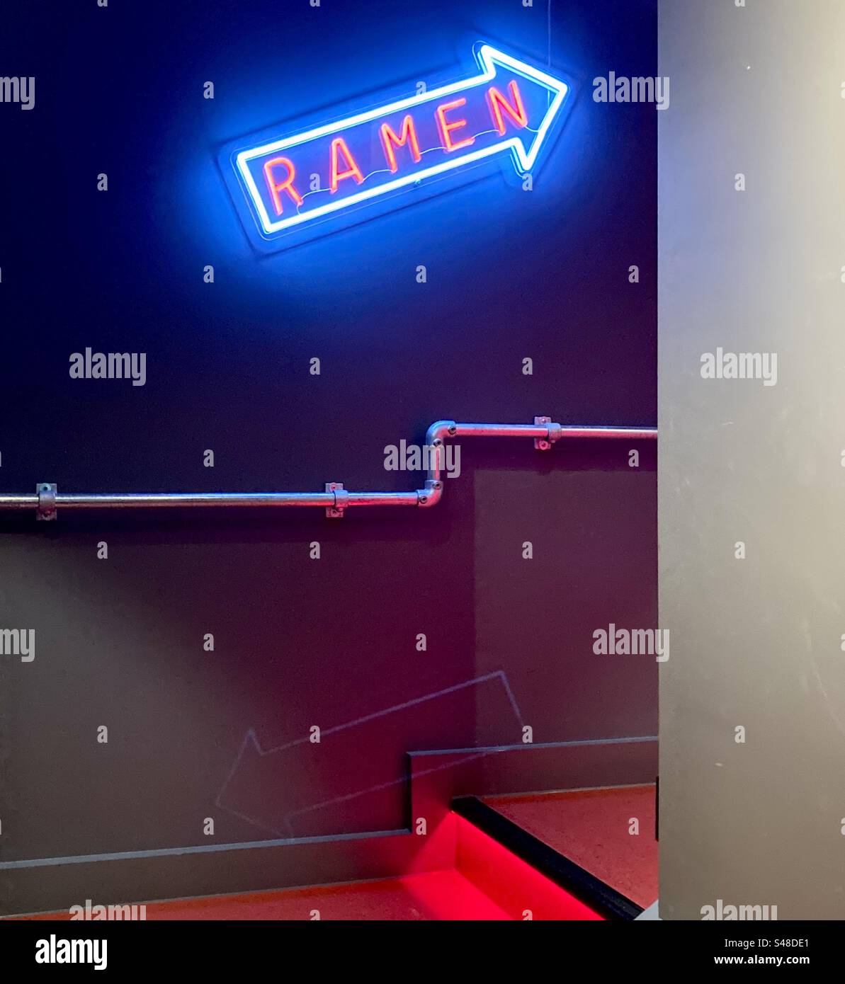 Neon sign saying ‘ramen’ in arrow pointing right and upstairs - Smartphone Captured Stock Image