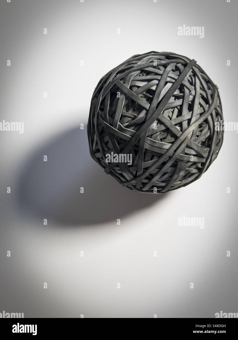 Black rubber band ball on a white background: Phillip Roberts Stock Photo