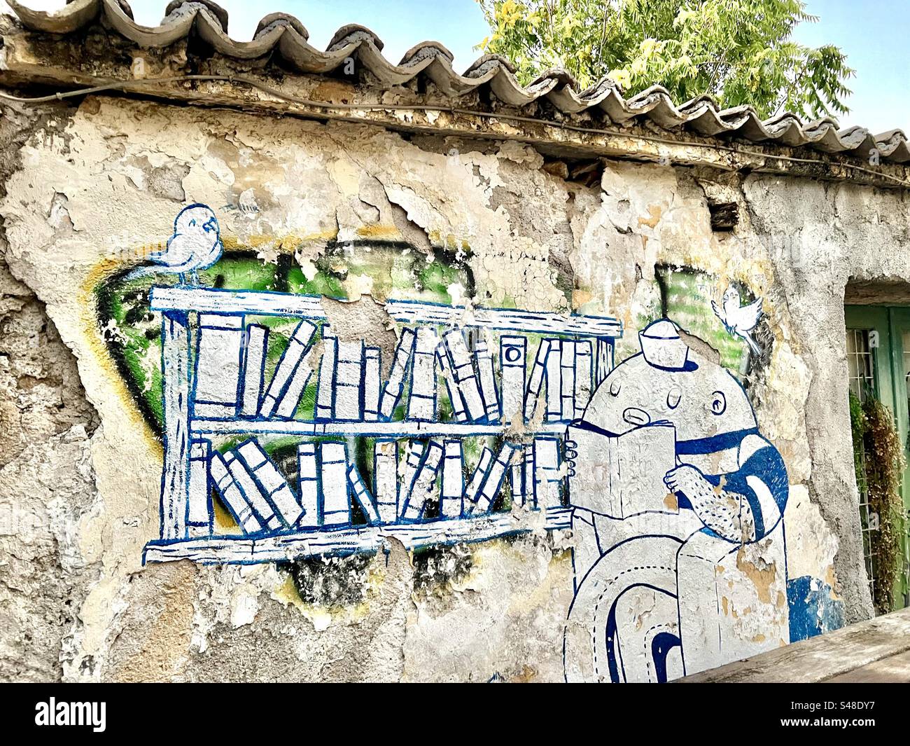 A mural is painted over older graffit on an exterior wall of a building at the corner of Thrasyvoulou and Klepsydra streets, Plaka district of Athens. - Smartphone Captured Stock Image