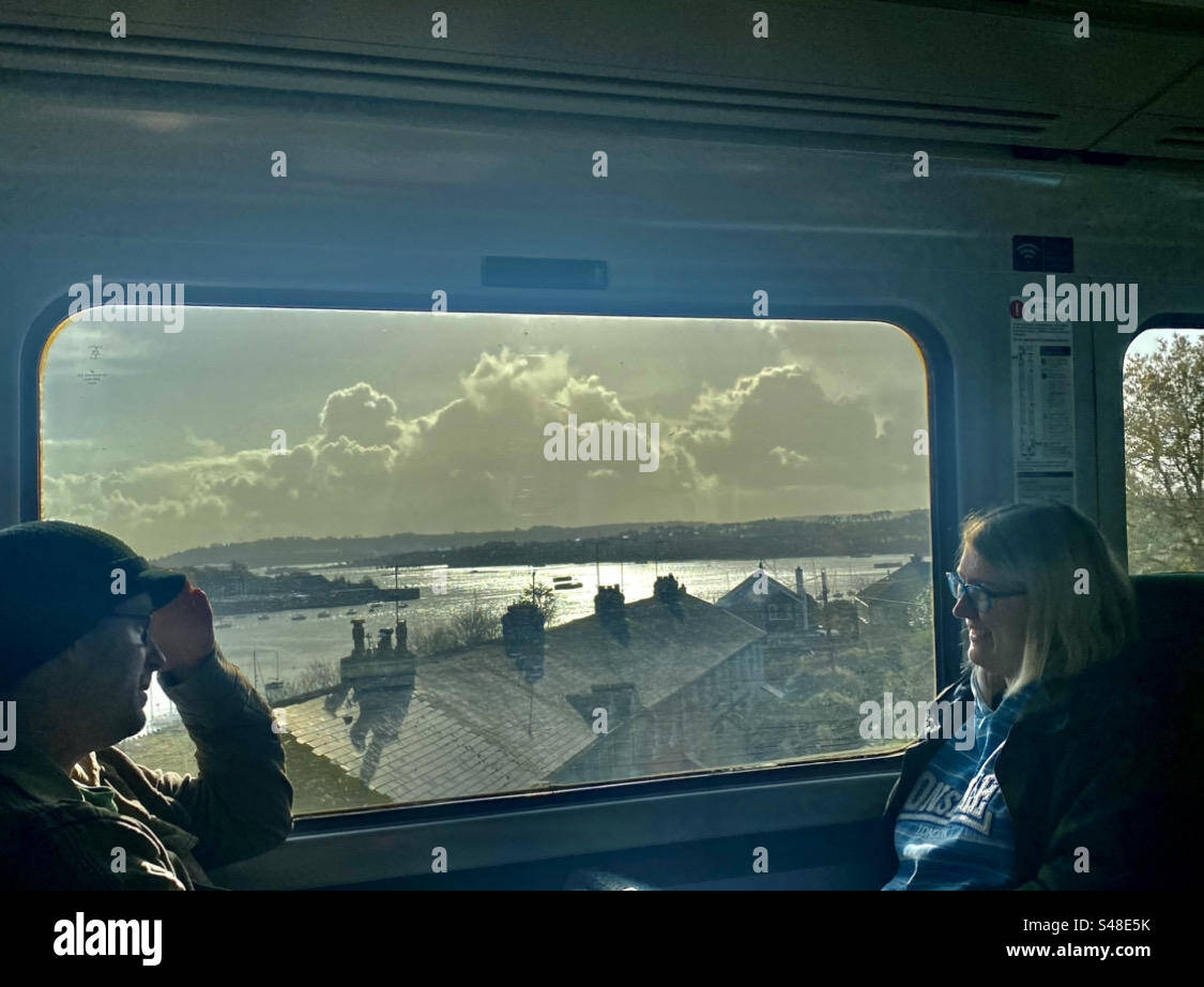 Train journey over river Tamar From Cornwall to Devon - two passengers on GWR sitting by window view of The Taymar - Smartphone Captured Stock Image
