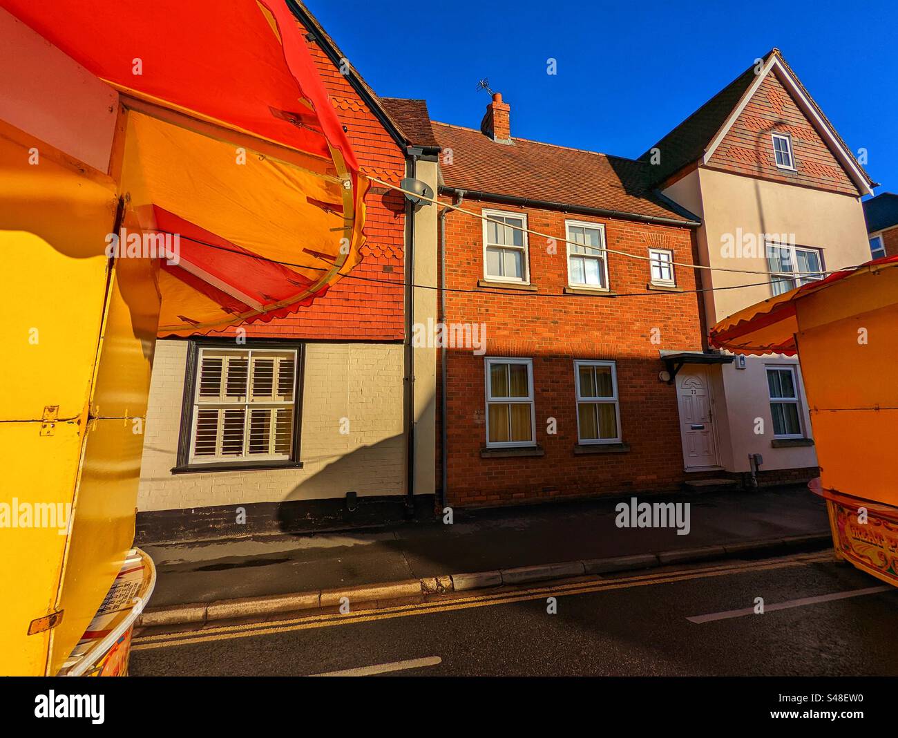 Houses seen between fairground tents, Ick Street Fair, Abingdon on