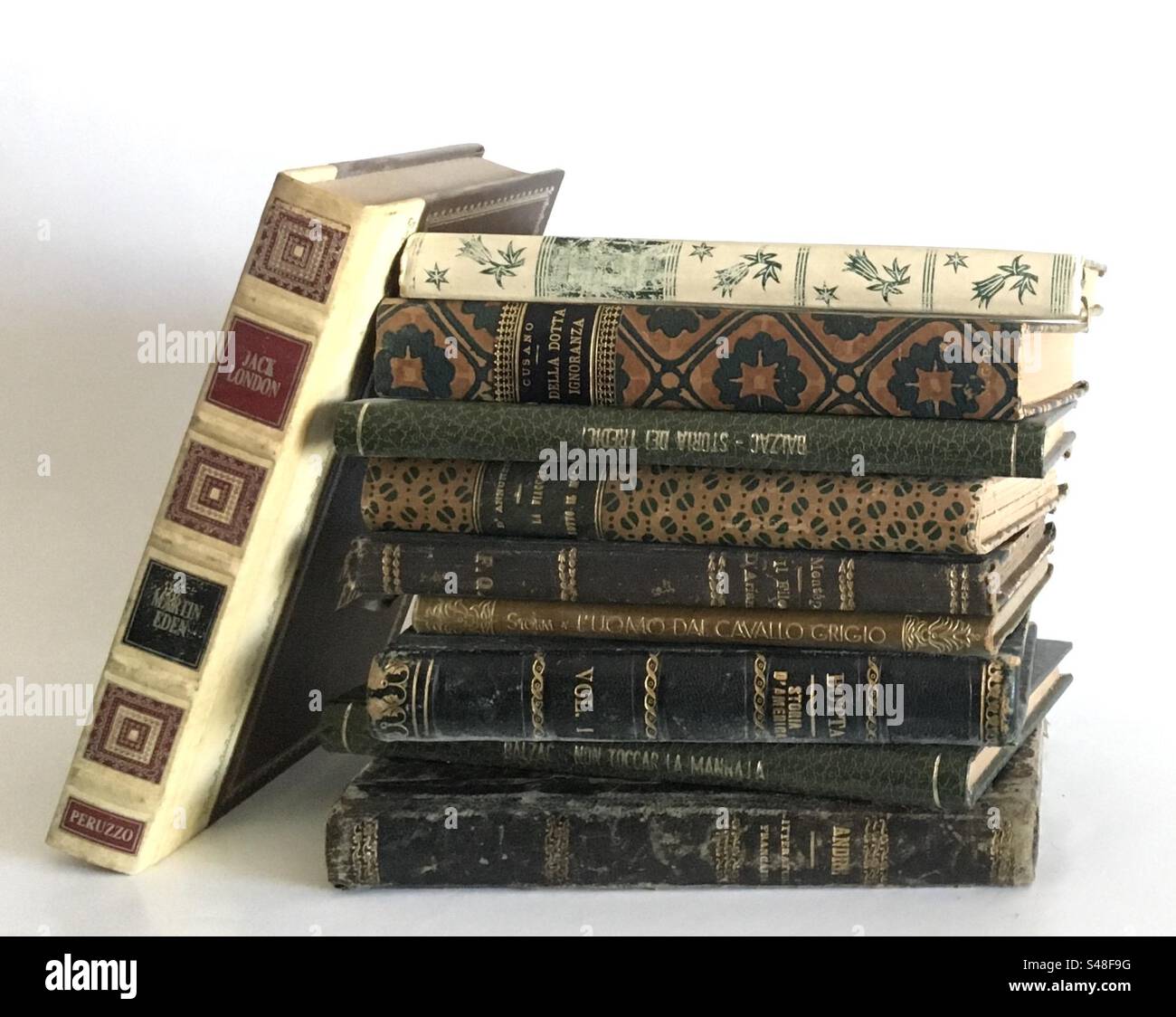 Pila di libri antichi su sfondo bianco. Libri rilegati con fregi in oro. Un libro appoggiato in diagonale. Stack of  ancient bound books with golden friezes on white background. - Smartphone Captured Stock Image
