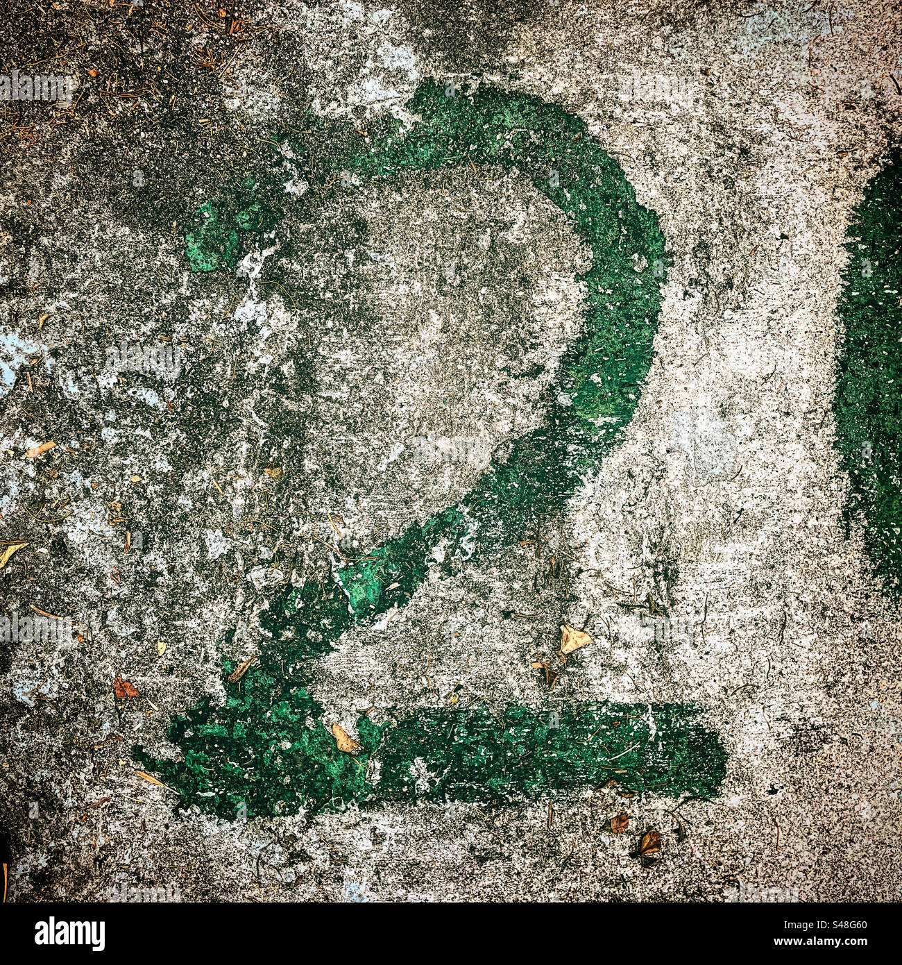 number 2 written in green paint on the textured rough graphic ground road in exterior view photo - Smartphone Captured Stock Image