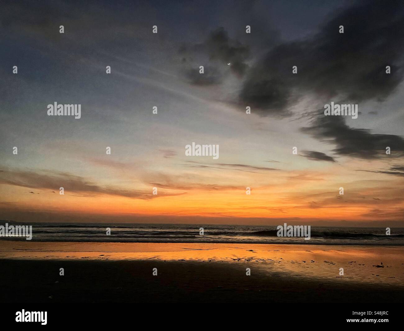 Sunset at Seminyak beach Bali with the sun set over the sea and the orange glow remaining in the clouds - Smartphone Captured Stock Image