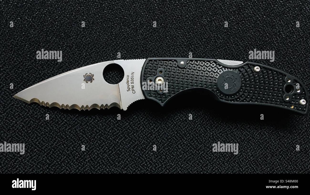 Close-up shot of a Spyderco Native 5 serrated locking pocket knife on black background - Smartphone Captured Stock Image