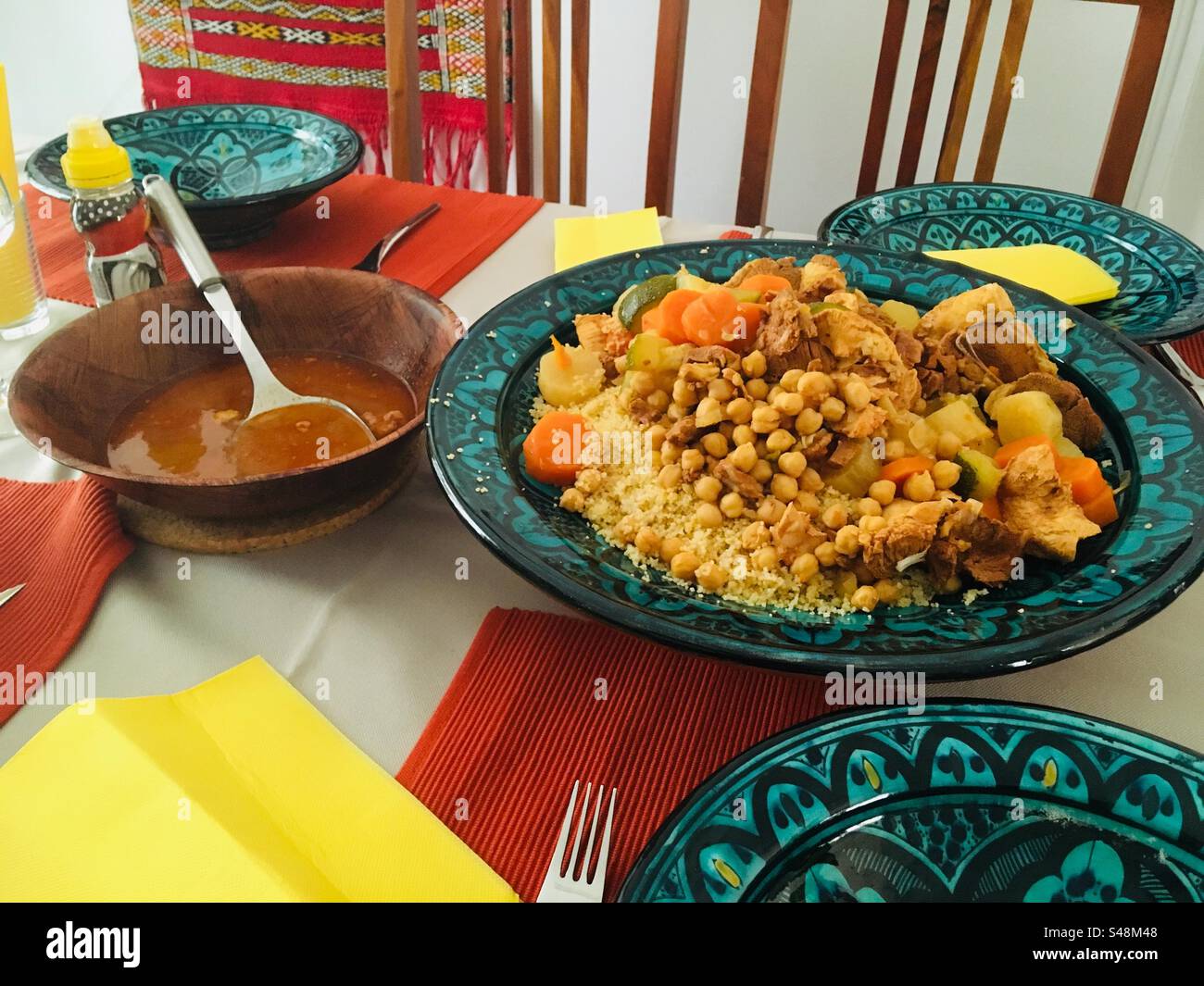 Coucous platter on a table and chairs. Served with sauce on blue intricate plates - Smartphone Captured Stock Image