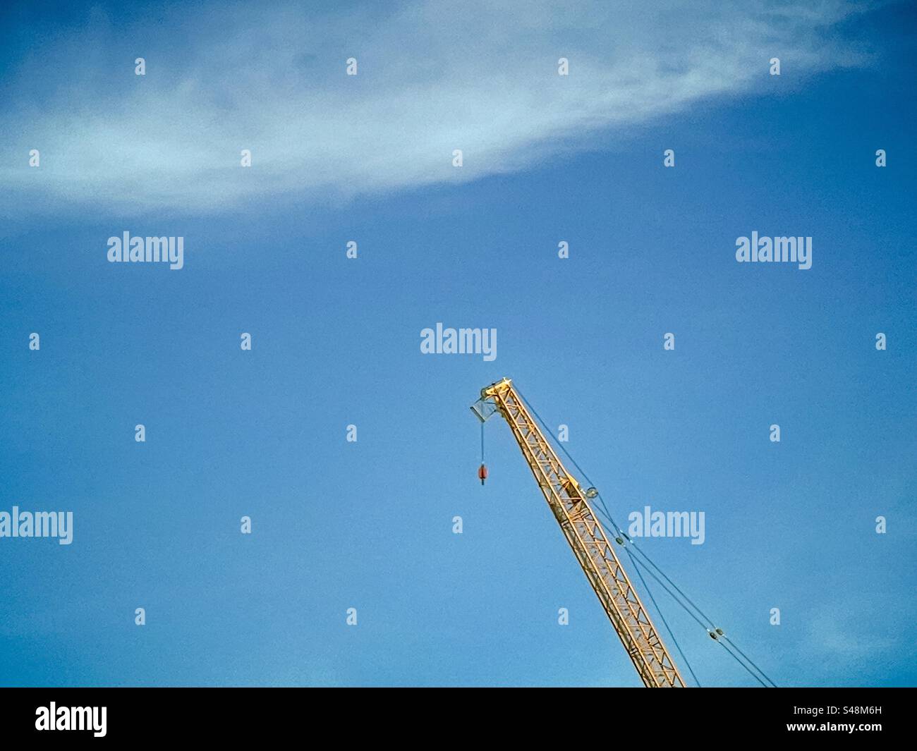 Construction crane on blue sky under white clouds. Stock Photo