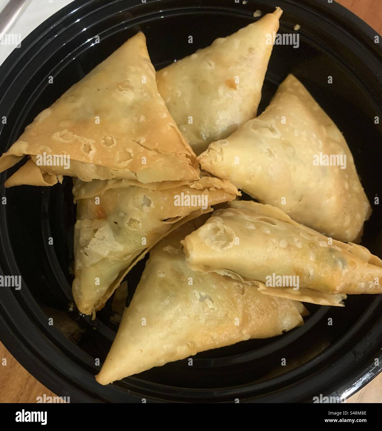 Closeup image of freshly prepared chicken samosas in a black plastic take-away plate - Smartphone Captured Stock Image