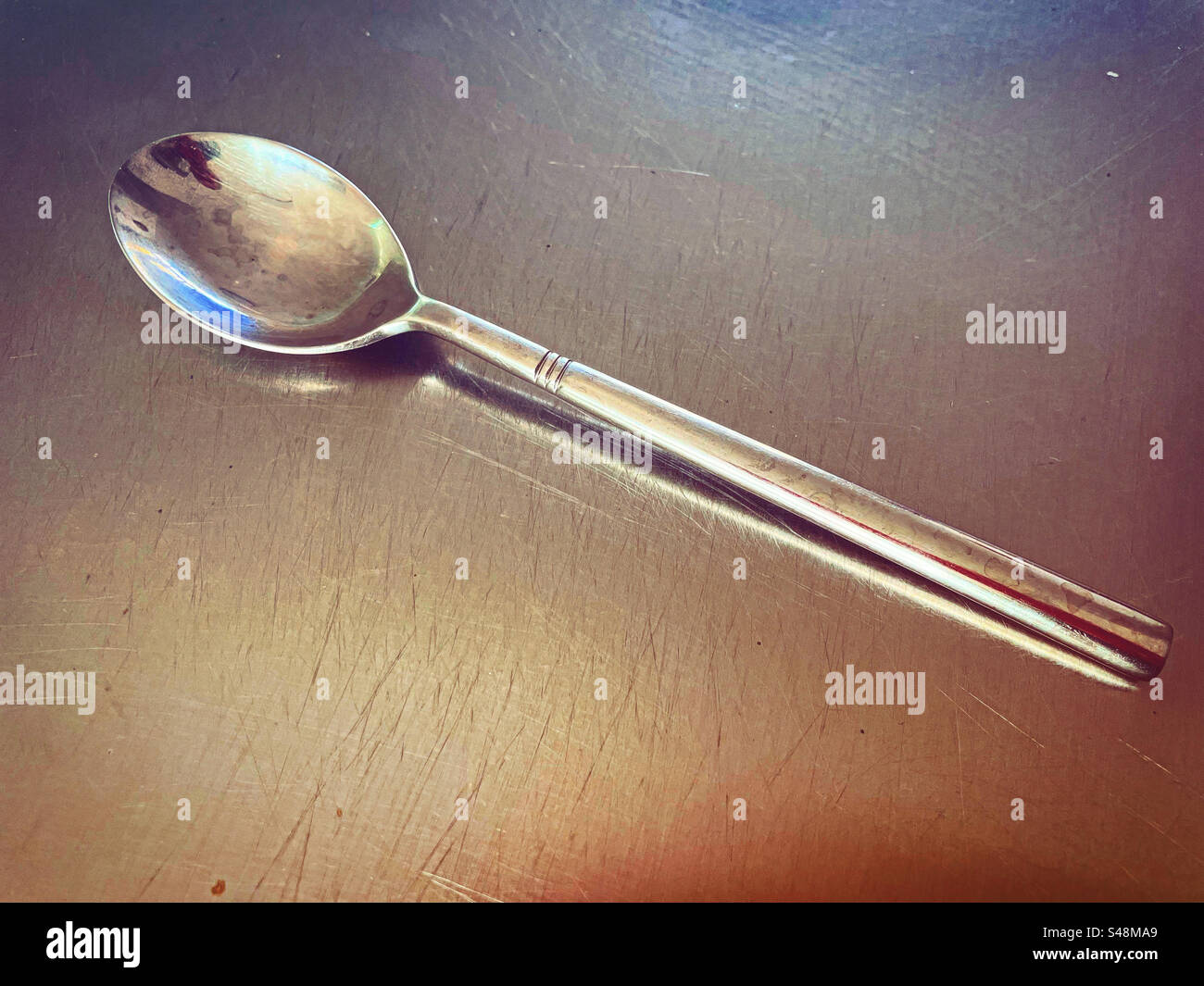 silver spoon on a silver plate artwork top in a kitchen teady to use as it is super clean and shiny shine bright in metal for eating luxury close up o - Smartphone Captured Stock Image