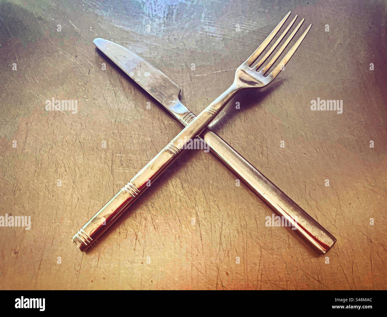 silver knife and fork on a silver plate on a metal steel kitchen worktop in a restaurant ready to be use as they are super clean shiny shine dish for eating eat - Smartphone Captured Stock Image