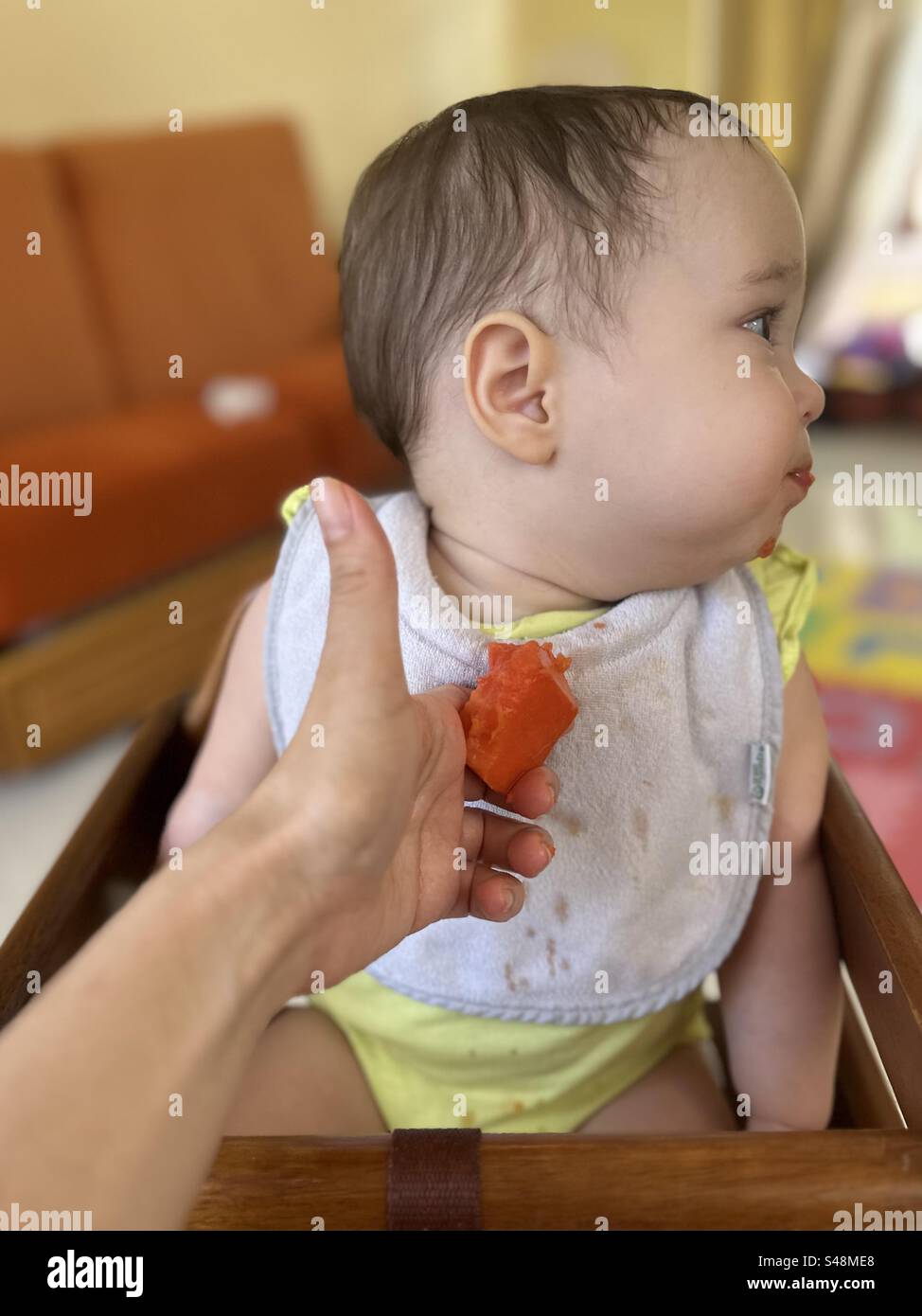 Baby eating papaya for the first time. Baby refusing to eat Stock Photo