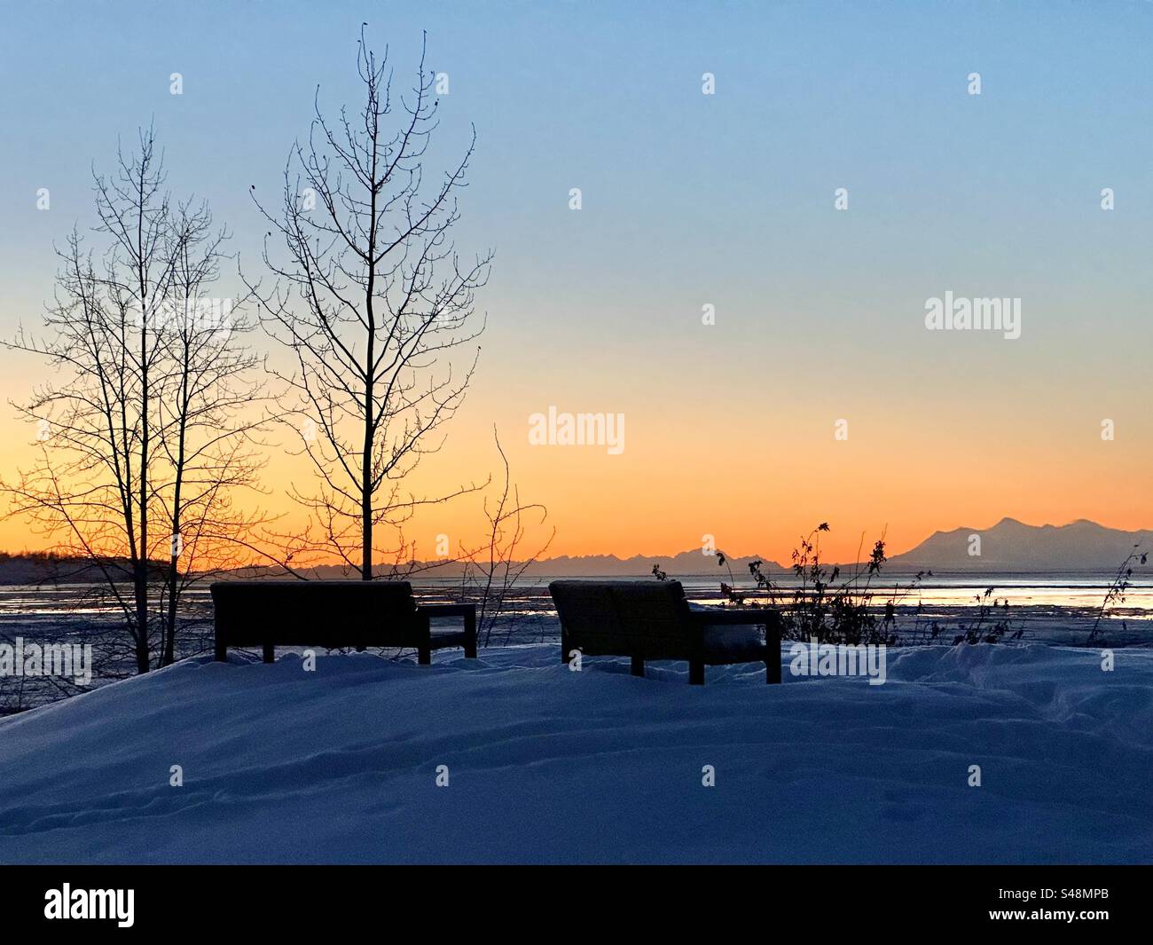 Two lonely benches covered in snow in Anchorage Alaska Stock Photo