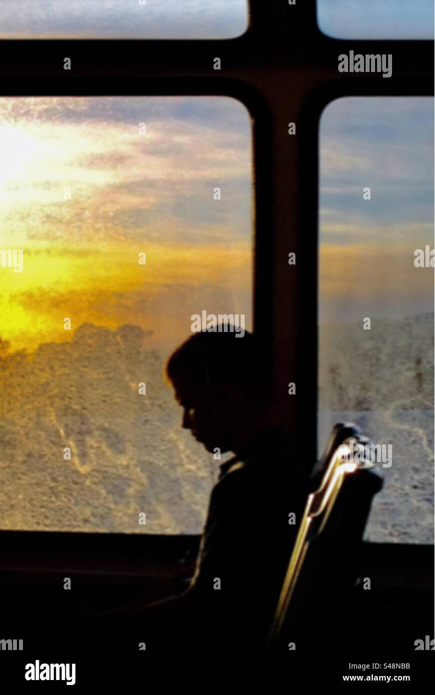 Silhouette of a girl on a bus with a sun set through the window - Smartphone Captured Stock Image