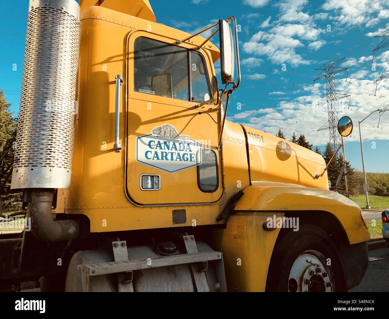 Yellow Canada Cartage truck on an azure blue cloudy sky Stock Photo