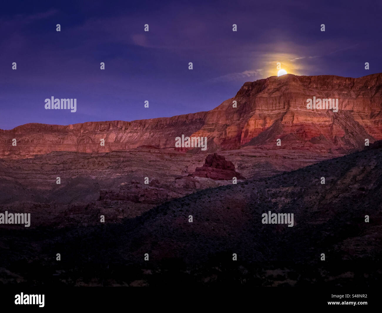 A full moon rises over the mountains in the Virgin River Gorge at Cedar Pocket, near Littlefield, Arizona - Smartphone Captured Stock Image
