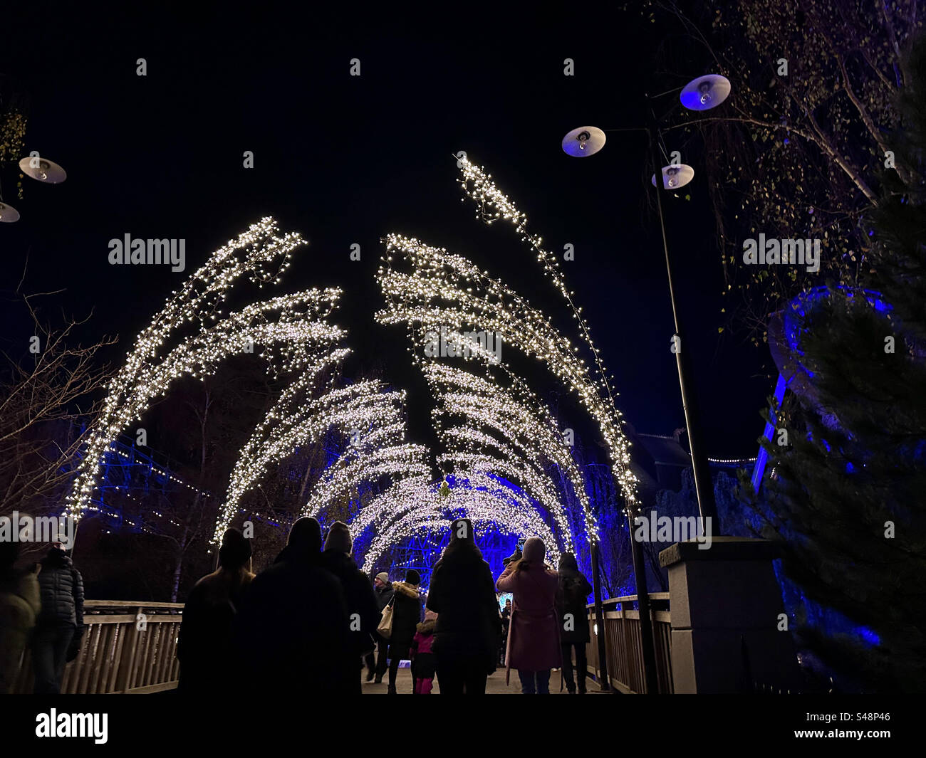 A winter scene as people walk beneath an arch of fairy lights at Liseberg theme park, Gothenburg Sweden at Christmas. - Smartphone Captured Stock Image