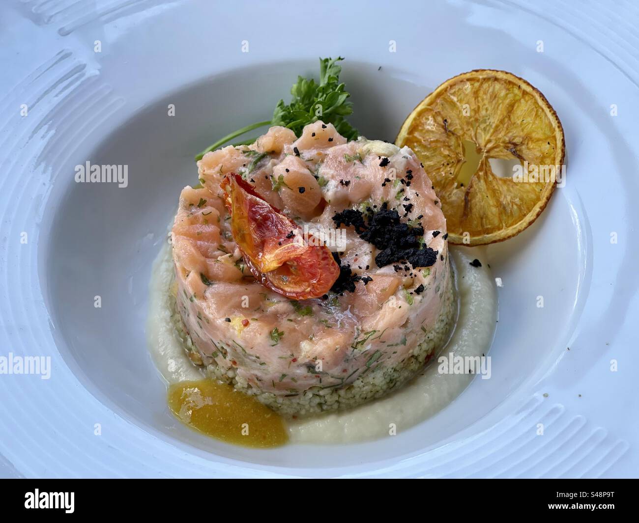 Close-up shot of a Salmon Tuna ceviche cold salad on a deep restaurant plate with lemon - Smartphone Captured Stock Image