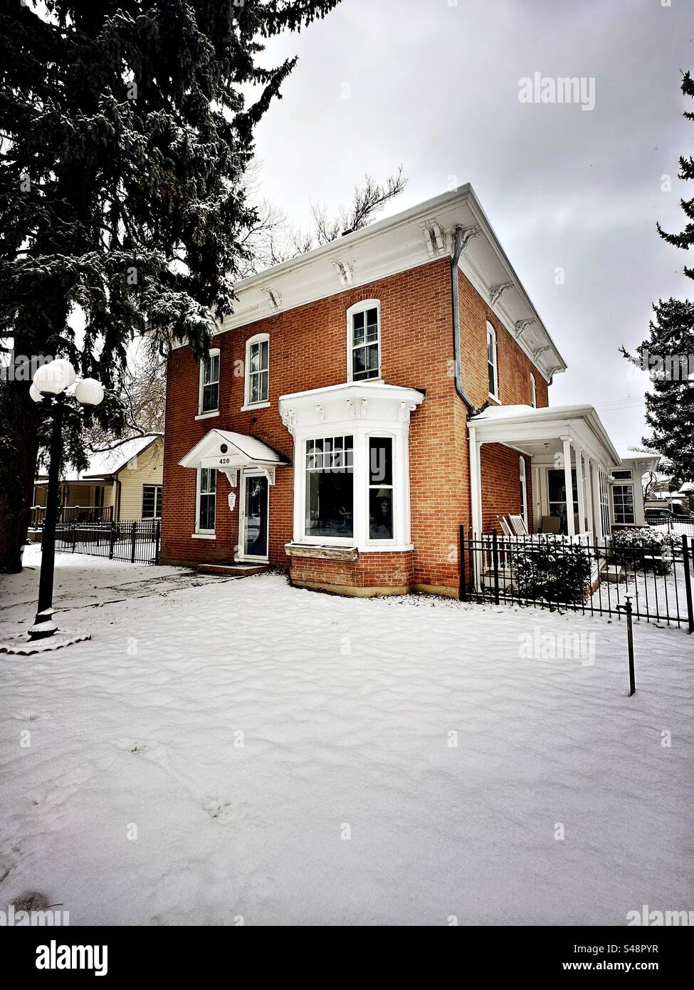 Longmont, Colorado, USA - November 2023:  Red brick family house on a snowy day. Located in downtown, historic district. - Smartphone Captured Stock Image