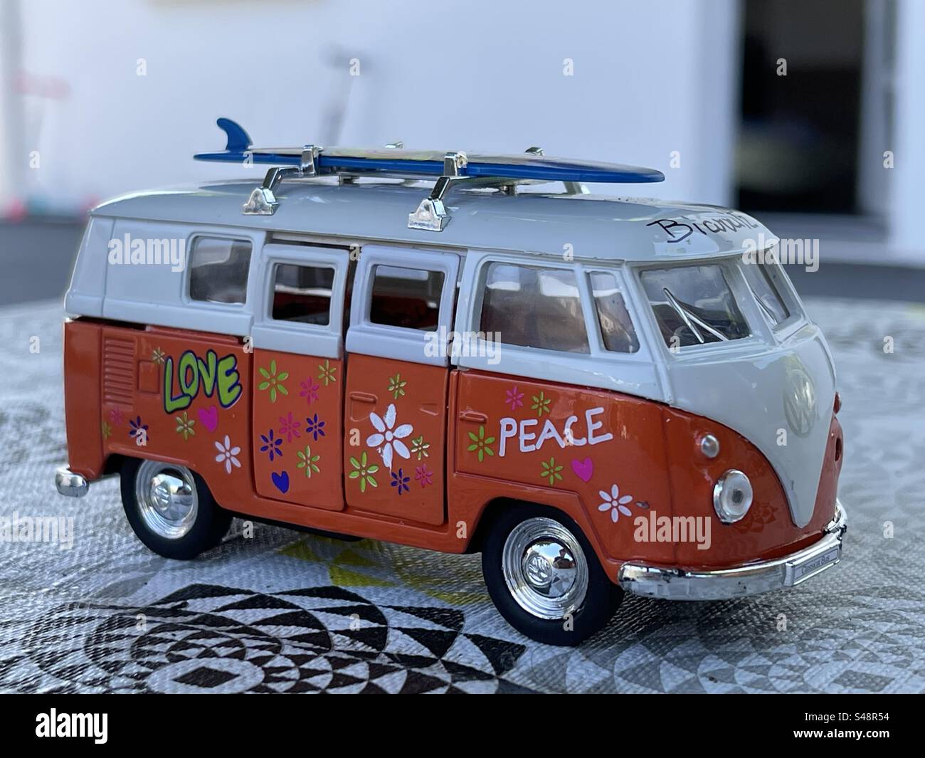 Close-up shot of a Volkswagen mini-bus model car with a surf board on its roof, peace and love and flowers on its side Stock Photo