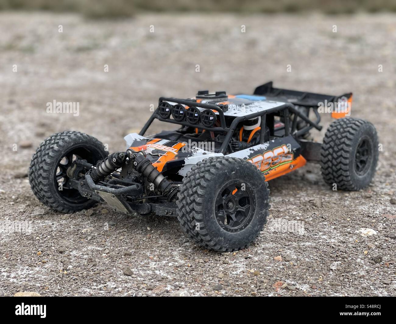 Shot of a dusty DB8SL Remote controlled off-road RC car buggy on the ground with blurry background - Smartphone Captured Stock Image