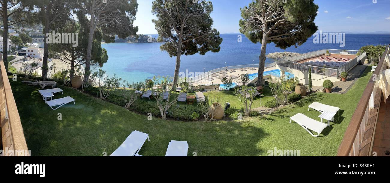 Panorama of a hotel front lawn patio with lawn chairs over the Mediterranean in Roses, Costa Brava, Spain - Smartphone Captured Stock Image