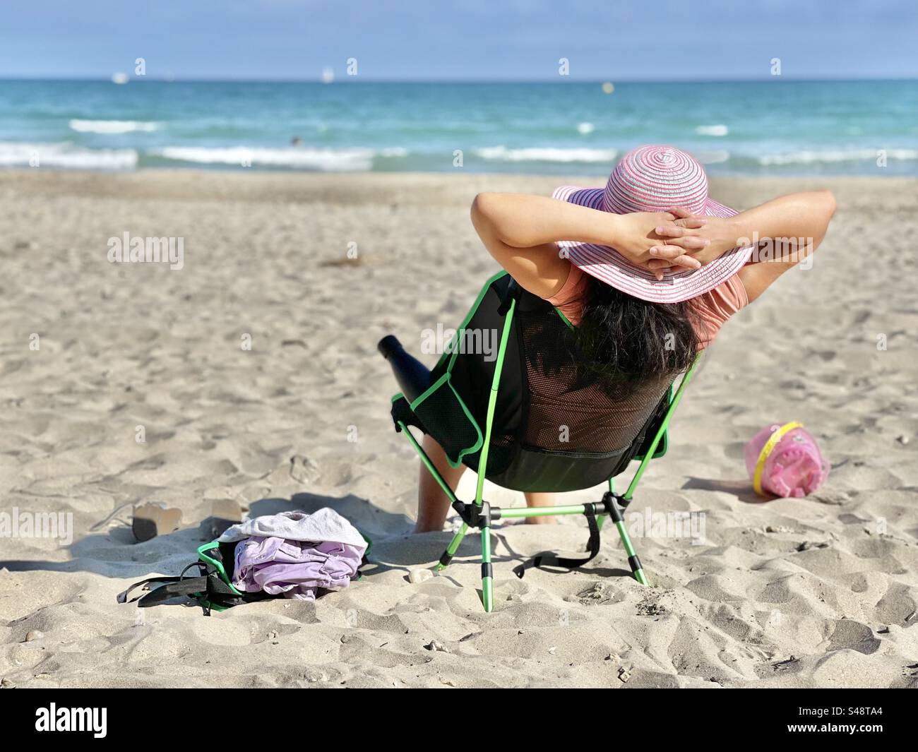 Landscape shot of a young Asian Filipina woman sitting and relaxing on the beach in Palavas-les-flots, Occitanie, France - Smartphone Captured Stock Image