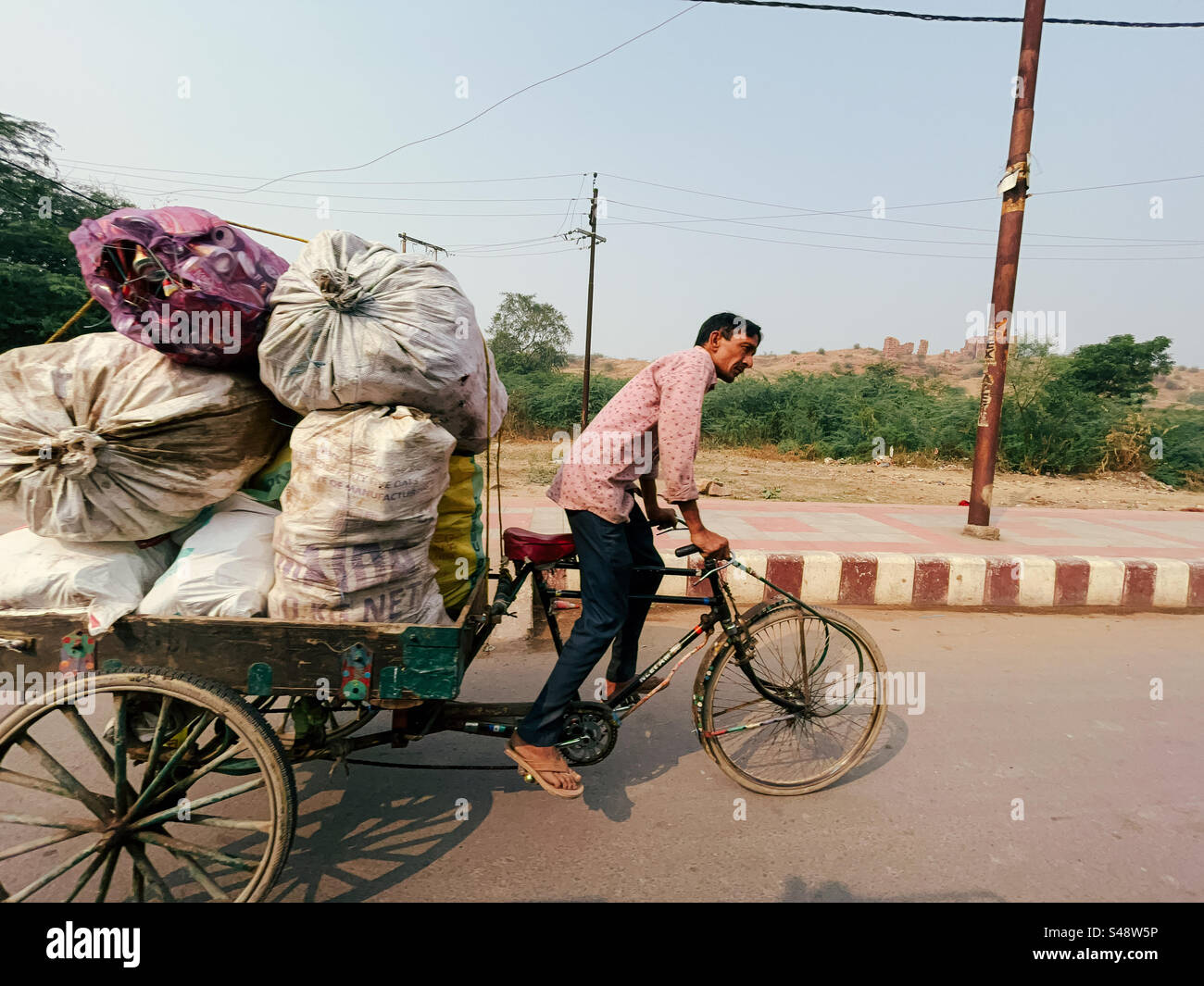 An indian man transporting goods to a market in a modified bicycle - Smartphone Captured Stock Image