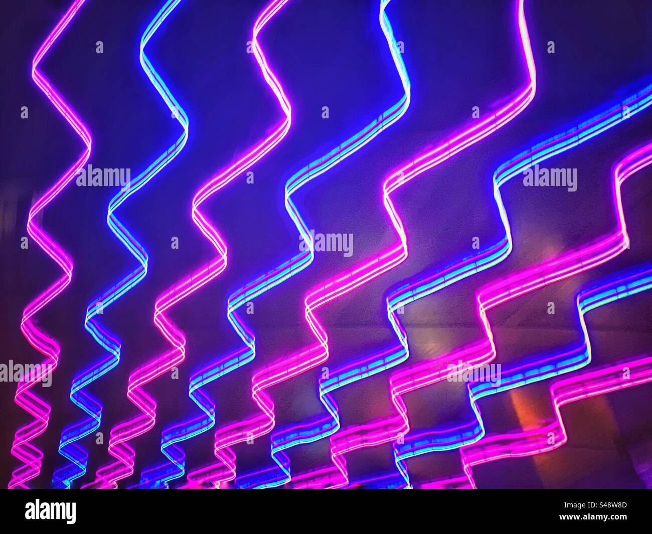 Neon pink and blue zigzag chevron pattern lights. Funky background texture Stock Photo